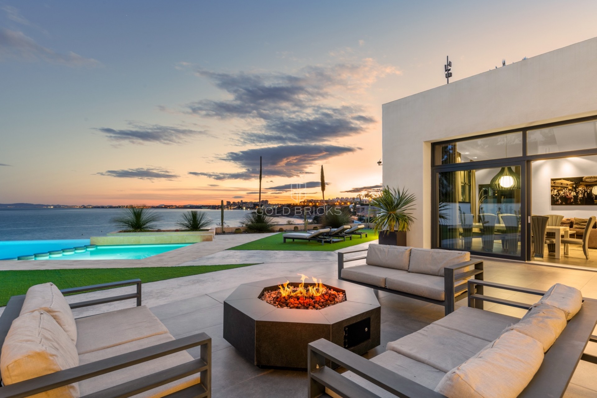 Terraza con fuego exterior y vistas al mar al anochecer en la villa de Cabo Roig