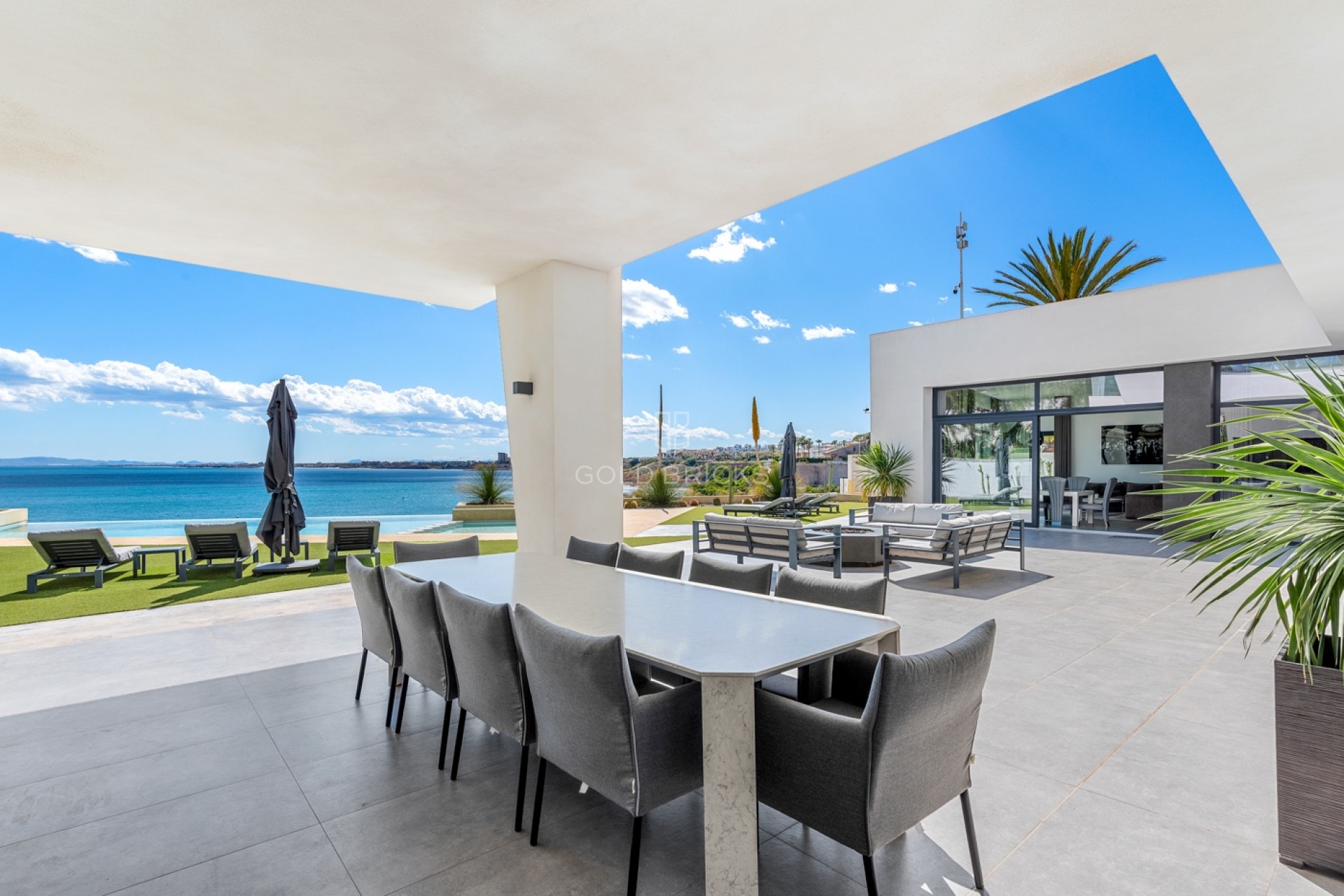 Terraza cubierta con mesa de comedor frente al mar, lugar de conversación