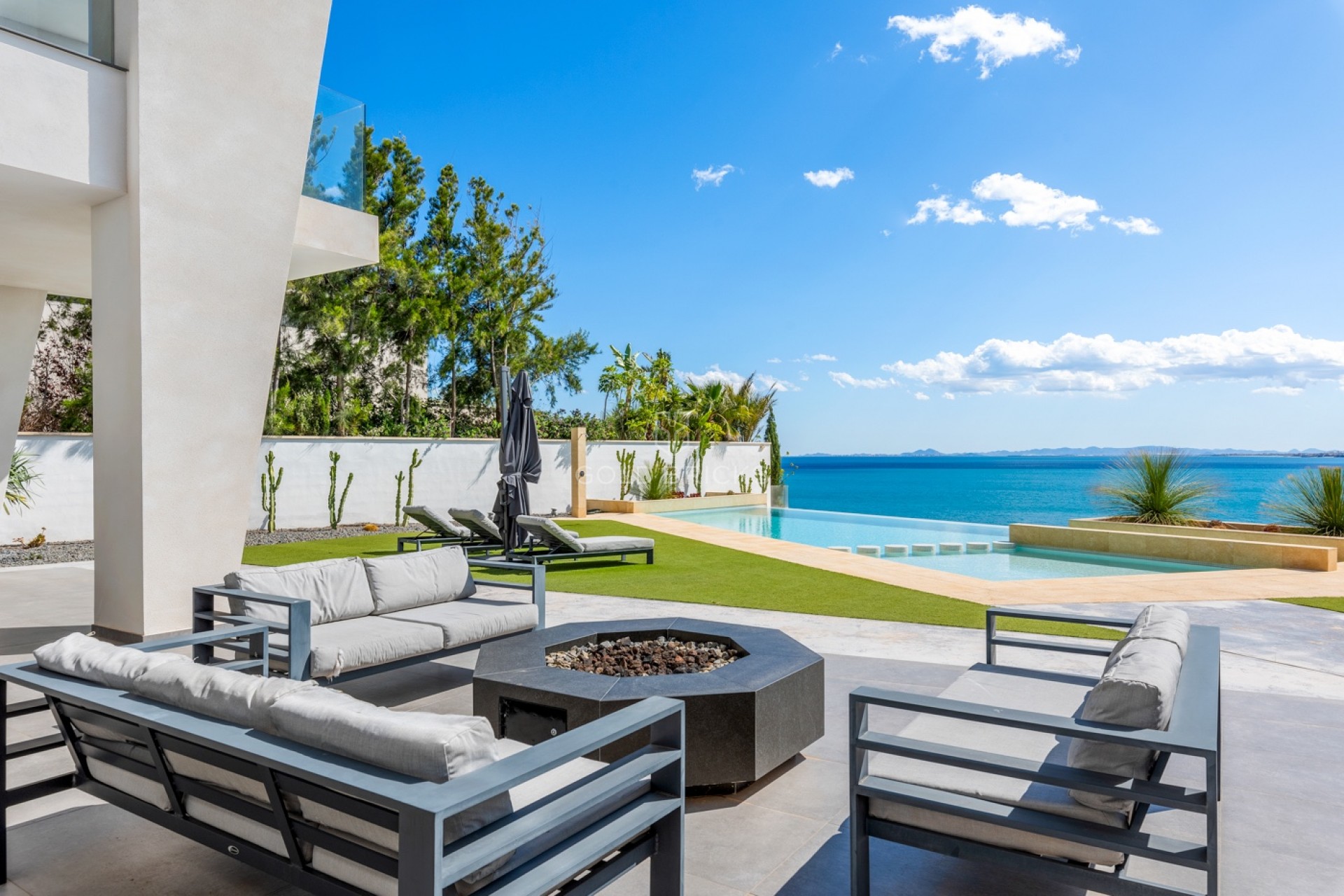 Terraza de villa en primera línea con chimenea exterior y piscina infinity frente al Mediterráneo